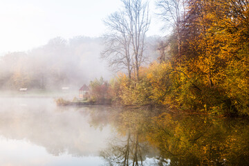 Naklejka na ściany i meble Beautiful landscape with lake and forest. Amazing nature wallpaper. Autumn trees in foggy morning. Romantic place. 