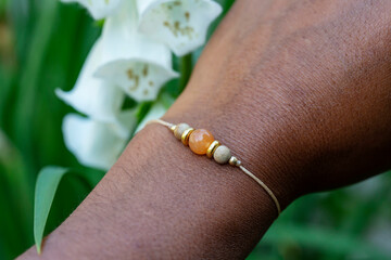 outdoor closeup of a hand wearing tiny jewelry bracelet with mineral bead stone