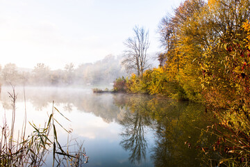 Beautiful landscape with lake and forest. Amazing nature wallpaper. Autumn trees in foggy morning. Romantic place. 