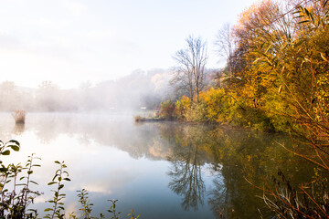 Fototapeta na wymiar Beautiful landscape with lake and forest. Amazing nature wallpaper. Autumn trees in foggy morning. Romantic place. 