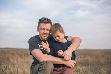Dad hugging son  on the  meadow background. Concept of father-son relationship