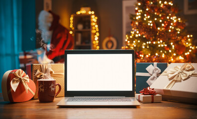 Blank laptop and Santa Claus bringing gifts