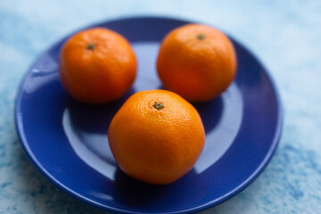 three tangerines on a plate closeup photo with vibrant colors