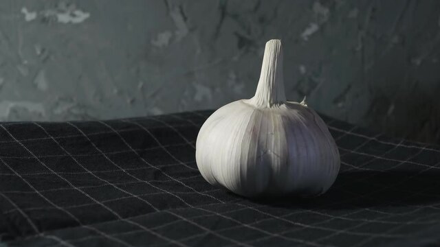 head of garlic close-up against a background of dark fabric. The garlic rotates slowly. Eco friendly food concept.