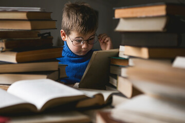 pretty child boy in glasses  looking into open book of magic and reading it