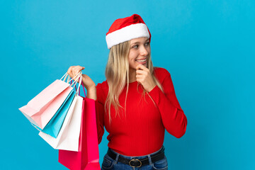 Obraz premium Woman with christmas hat going to buy something isolated on blue background thinking an idea and looking side