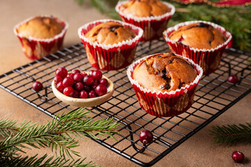 Christmas muffins with cranberries on a brown background, fir branches, closeup