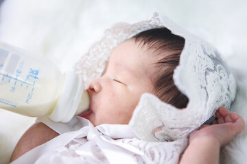 Asian newborn baby was sleeping on the bed with milk, white sheets.