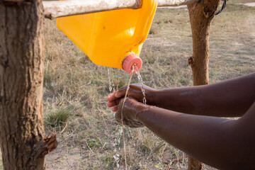 Pouring water from the innovation tool called tippy tap made of 5 liter can of water and a string,...