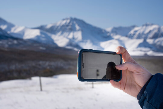 Taking a picture of the Canadian Rockies with a smartphone while travelling on a road trip.