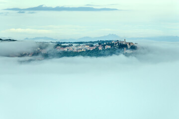 hilltop village and low morning clouds, shot from Montepulciano historical town, Siena, Italy