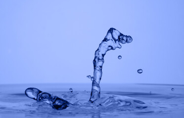 Water drop falling down. Abstract blue background.