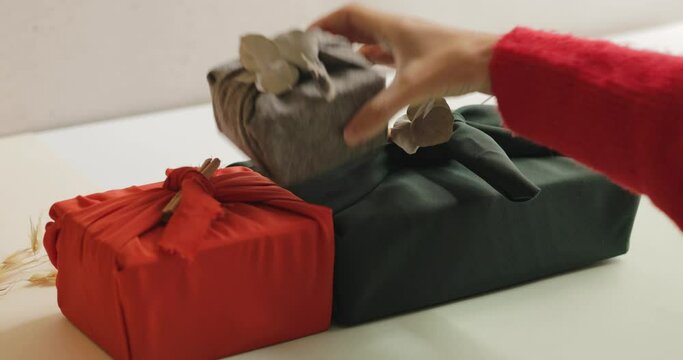 Young woman taking out and putting wrapped gifts on the table, Christmas and New year minimalist concept. 4k