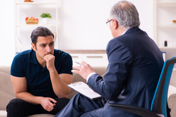 Obraz premium Young man visiting old male psychologist