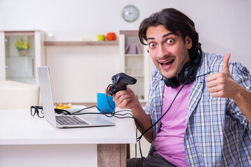 Young male student playing computer games at home