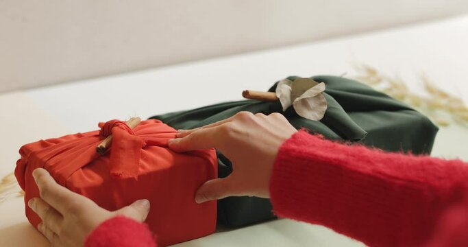 Young woman wearing red sweater arranging wrapped gifts on a table, Christmas and New year minimalist concept. 4k