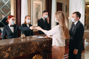 Check in hotel. receptionist at counter in hotel wearing medical masks as precaution against virus. Young woman on a business trip doing check-in at the hotel