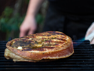 a man sets fire to a large steak with a gas burner on the grill. flambe.