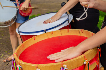 Detalhe de mãos em instrumentos de percussão. Mulheres protestam em apoio a uma jovem brasileira que foi estuprada em uma festa. 