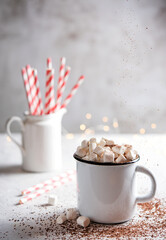 hot chocolate with marshmallows and a red paper tube on a gray table. Christmas photo.