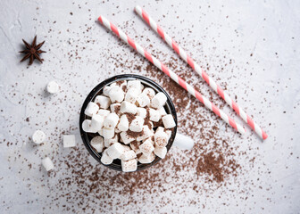 hot chocolate with marshmallows, anice star and a red paper tube on a gray table. Christmas stillife