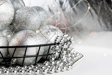 Christmas composition. Christmas balls and silver beads in an iron basket on a white background.