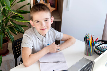 Distance learning online education. A schoolboy is studying at a computer at home and doing school...