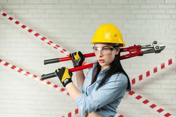 portrait of a female construction worker in a hard hat with a bolt cutter in her hands