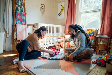 Happy mom and dad playin with baby in sunlight filled nursery