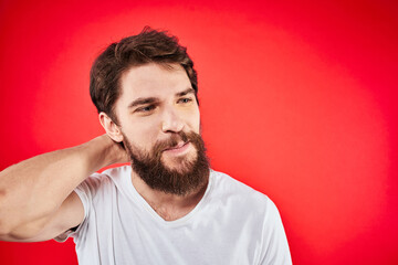 Obraz premium A man in a white T-shirt with a beard gestures with his hands emotions red background