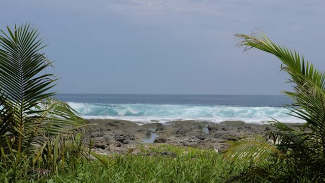 Ultra slow motion shot waves coming in behind rocks at Asu Island, North Sumatra, Indonesia