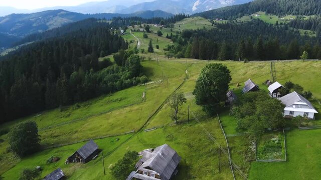 Fly over the small village in the Carpathian mountains. Aerial footage of a sunny summer evening in the contryside