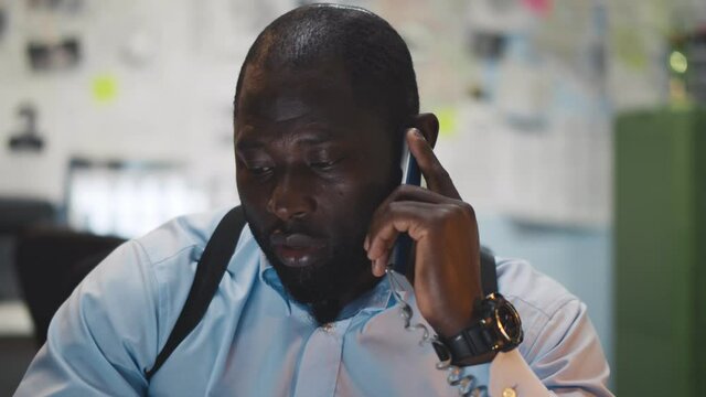 African Young Detective Sitting At Police Department Talking To Colleague On Phone