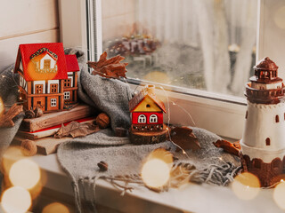 Home decoration for Christmas and New Year. A stack of books, a warm scarf and German traditional toy houses. Preparing for Christmas. Christmas mood. Place for your text. Interior decorations.