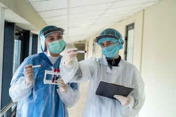 healthcare workers in protective mask, face shield and gloves write rezult test patient