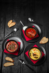 Laid table for a company with an assortment of soups: red borscht or kharcho, seafood cream soup or tom yam, tomato soup with beef or gazpacho. Festive table with delicious food.