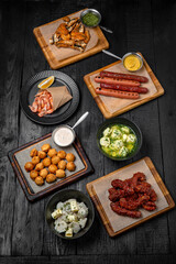 Laid table for a company with an assortment of dishes: fried sausages, dumplings, shrimps, fried chicken necks and fish backs. Festive table with delicious food.