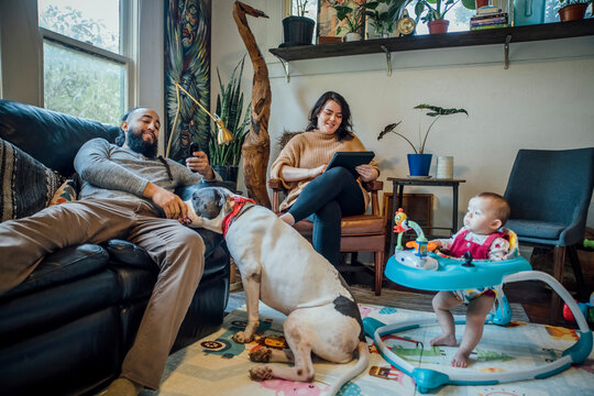 Family With Baby And Dog Hanging Out Together In Living Room Of Home