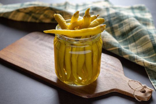 Front view of a jar of green peppers in vinegar.