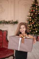A little girl opens a Christmas present from Santa. Christmas tale. Happy childhood