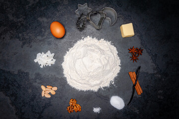 Several Ingredients for Cookies displayed in a circle on a slate plate. A pile of flour in the center. Top shot.
