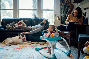 family with baby and dog hanging out together in living room of home