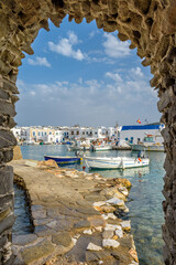 Traditional Cycladitic view of whitewashed houses with the christian church framed with a stone arch   in Naousa  Paros island, Greece