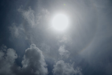 Naklejka na ściany i meble Dramatic sky bright sun behind cloud in blue sky