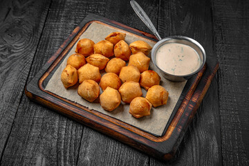 Deep-fried dumplings with garlic sauce on a background of black boards. Festive table with delicious food.