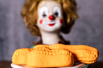 closeup of orange marshmallow circus peanuts with clown doll in background © zenmaster8