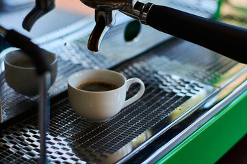 The process of making coffee in white ceramic cup on professional coffee machine.