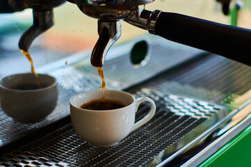 The process of making coffee in white ceramic cup on professional coffee machine.