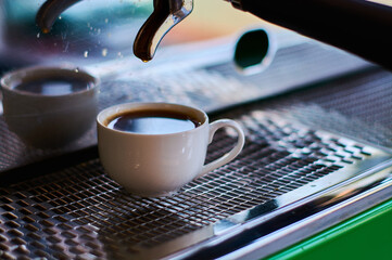 The process of making coffee in white ceramic cup on professional coffee machine.