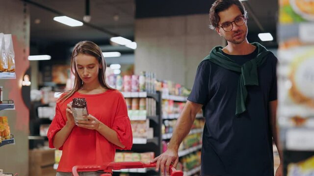 In Grocery Store Caucasian Couple Looking For Quality Product Checking Nutrition Value Expiry Date Communicating Enjoying Food Shopping.